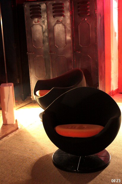 Paire de fauteuils Pod Egg Mars de Pierre Guariche vers 1970, accotoirs pleins, galbs sur assise hmisphrique; pitement tournant, recouvert d'un tissu noir, coussin orange.