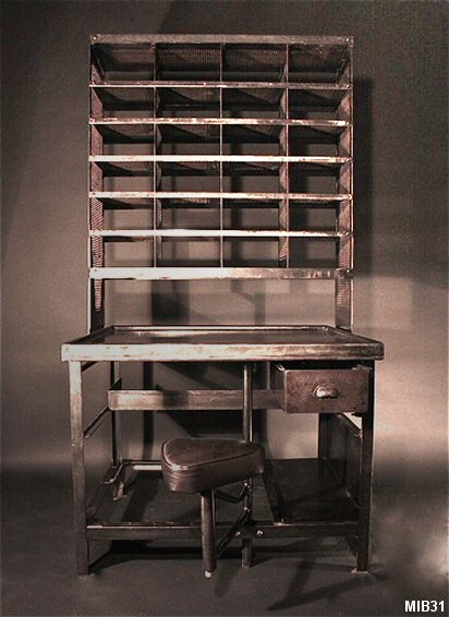 Bureau de tri postal, vers 1950, casiers ajourés en partie haute pouvant stocker des documents administratifs (21 x 29,7) et coulissants sur rail, finition métal graphite, siège en cuir.